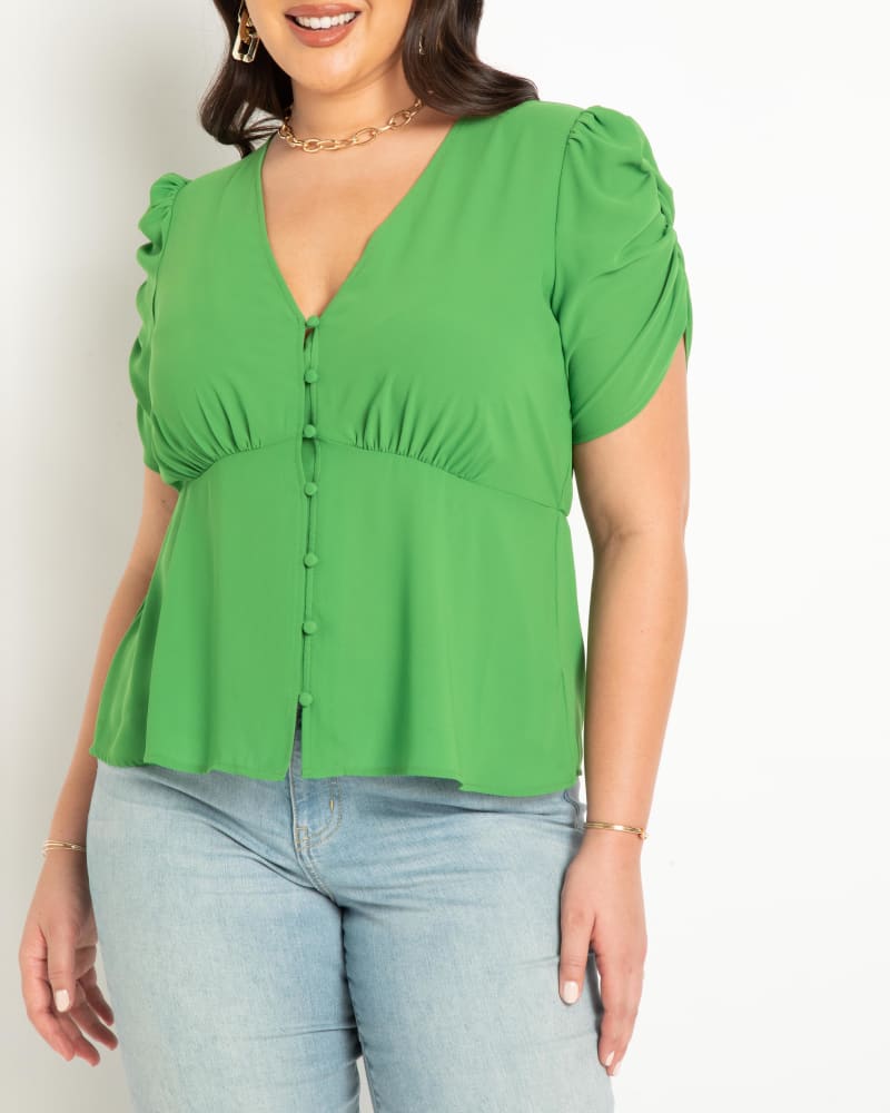 Front of a model wearing a size 14 V Neck Flat Peplum With Shirred Sleeve in Fern Green by ELOQUII. | dia_product_style_image_id:300082